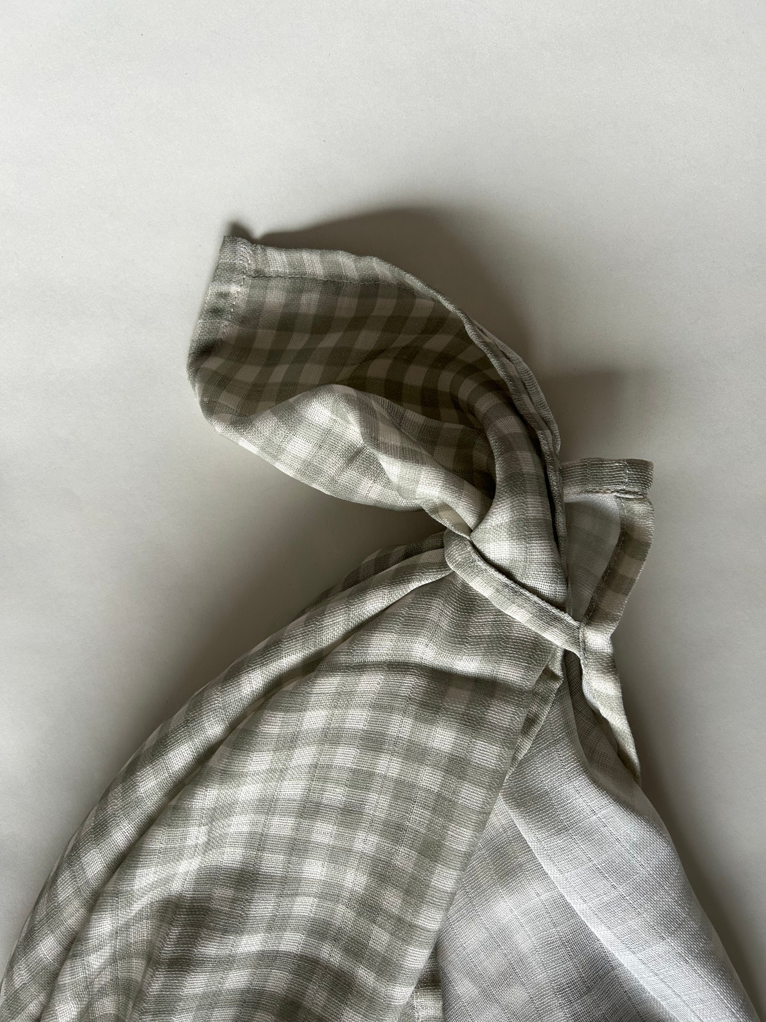 Gray and white checkered fabric tied into a knot on a light gray background