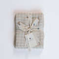 Folded checkered blanket with a bow and tags on a white background