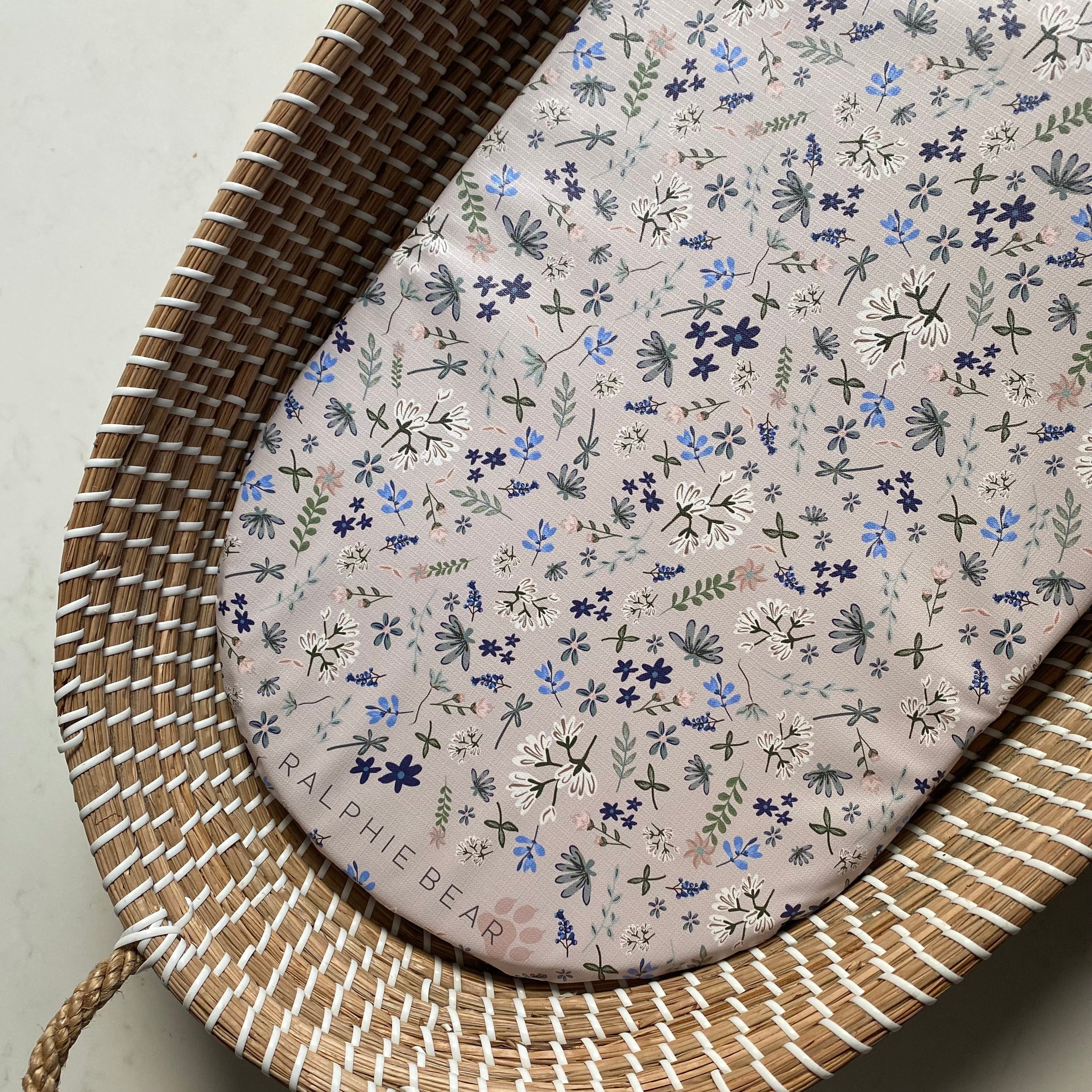 Woven basket with a floral-patterned cushion on a neutral background