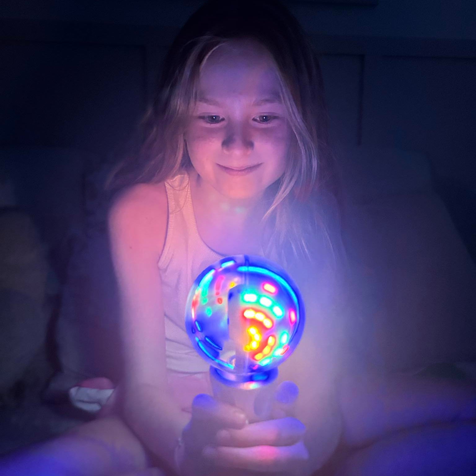 Child holding a glowing toy in a dark room