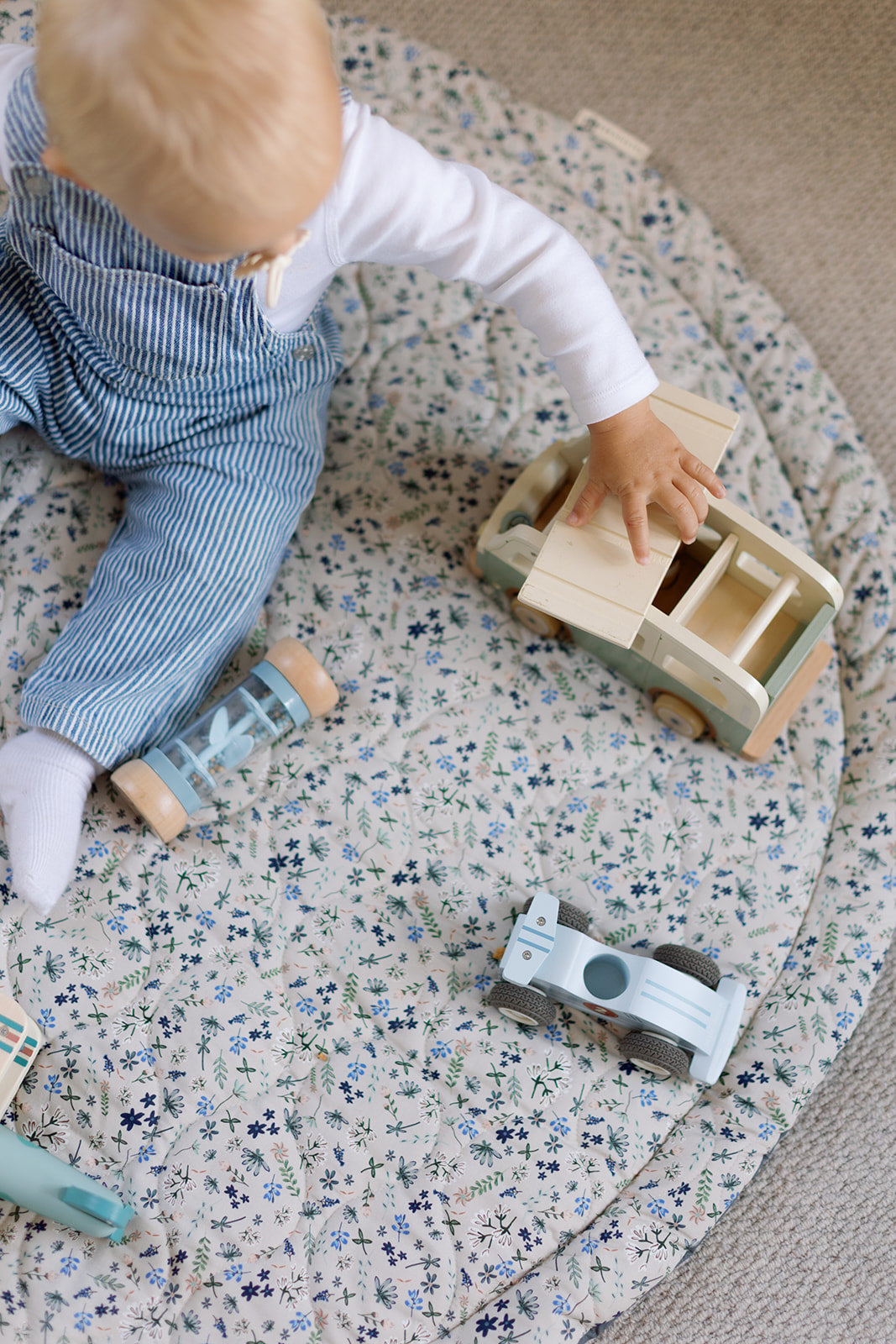 Child playing with wooden toys on a floral-patterned mat