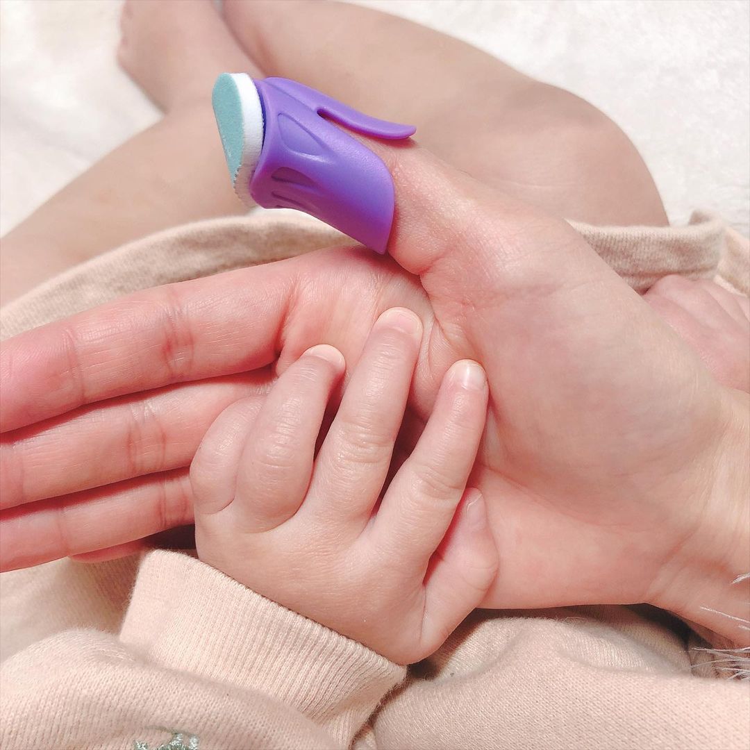 Baby hand with a purple and blue device on a white background